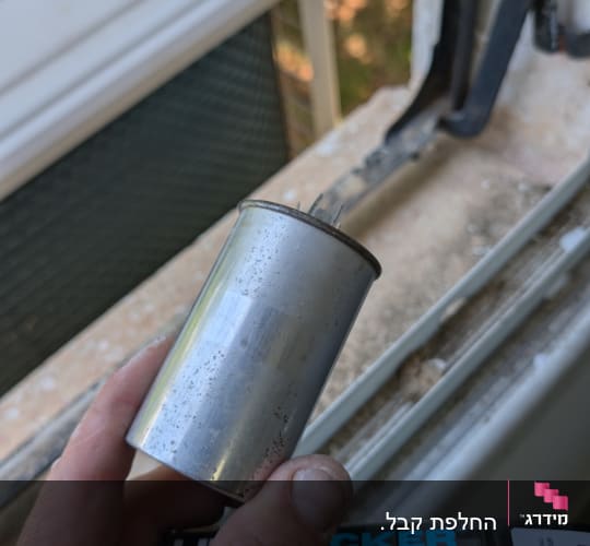 יד מחזיקה קבל ליד חלון עם מזגן